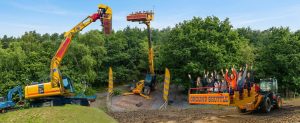 Panorama of three Diggerland construction machines for kids: the Spindizzy excavator ride on the left, the elevated Skyshuttle in the centre, and the Groundshuttle with cheering passengers on the right.